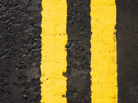 A painted double yellow line on a wet asphalt road surface.