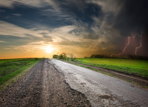 Asphalted road at sunset and stormy sky