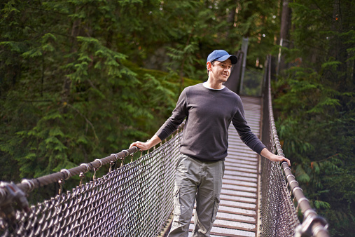 Shot of a young man crossing a bridge in a natural forest