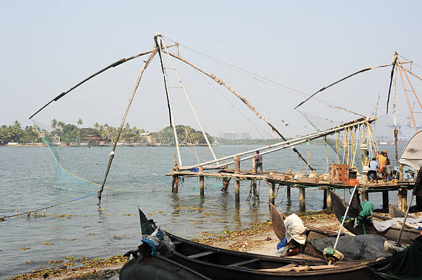Fishermen operate a Chinese fishing net Fort Kochi, India - 16 January 2015: fishermen operate a Chinese fishing net based on ancient technology and traditional materials, ropes and stones at Fort Kochi, Kerala, India cochin kerala india chinese fishing net stock pictures, royalty-free photos & images