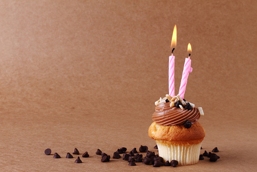 birthday cupcake with candles on chocolate background