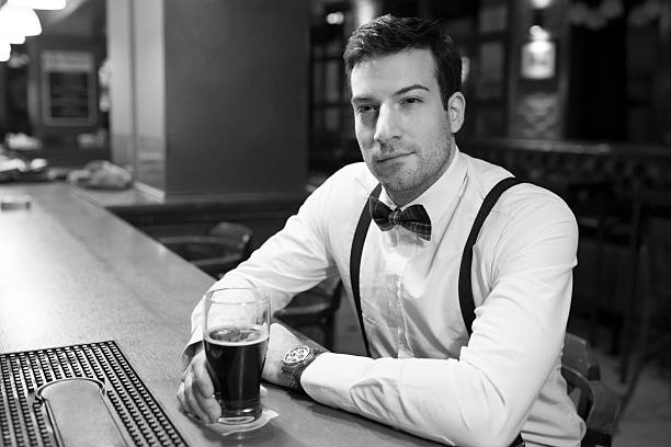 Close-up of a handsome young man spending time in the bar, drinking beer and relaxing.