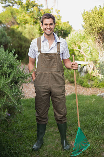 istock Young man in dungarees holding rake 465315274