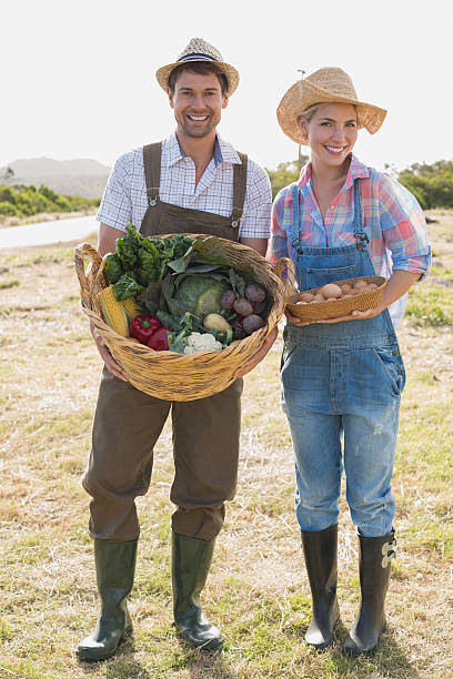 istock Smiling couple with vegetables standing in field 465315318