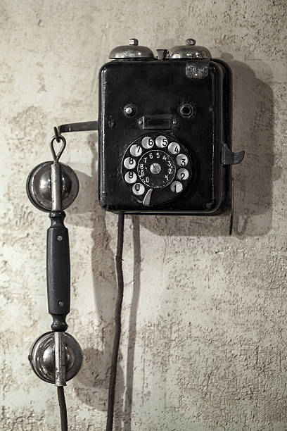 istock Vintage black phone hanging on old gray concrete wall 465315325