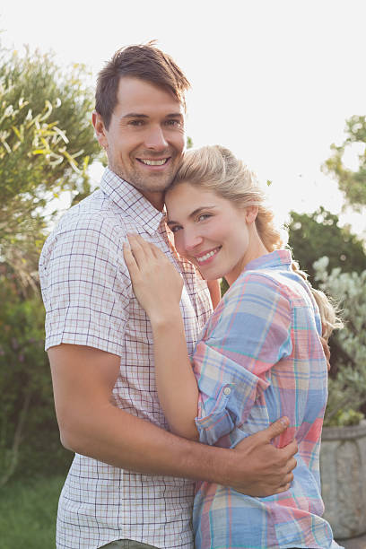 istock Smiling young couple embracing in the park 465317572