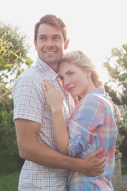 istock Smiling young couple embracing in the park 465317578