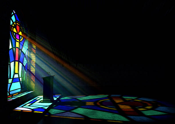 A reflection from a stained glass window of a church A dim old church interior lit by suns rays penetrating through a colorful stained glass window in the pattern of a crucifix reflecting colours on the floor and a speech pulpit stained glass photos stock pictures, royalty-free photos & images