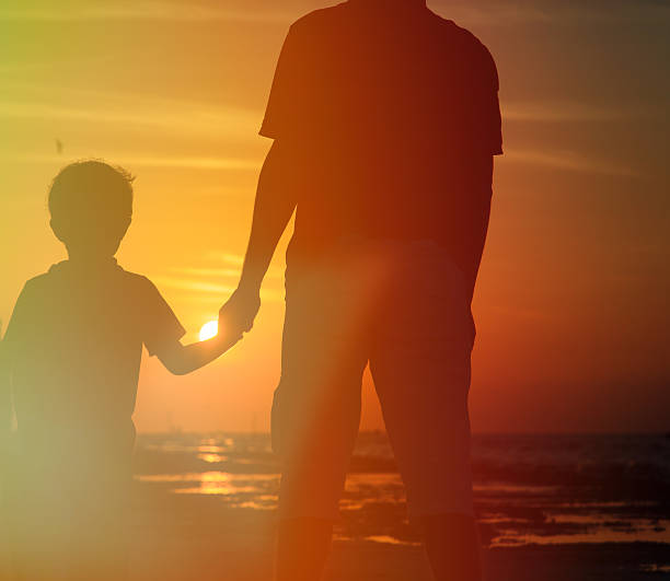istock father and son holding hands at sunset 465322164