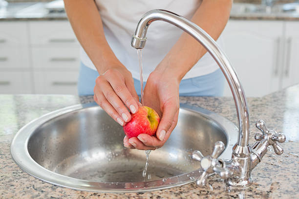 istock Mid section of hands washing apple at washbasin 465322300