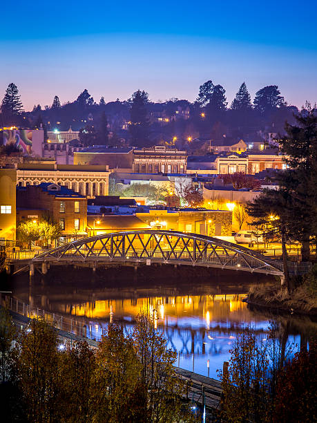 Petaluma Historic Downtown Dusk The historic downtown Petaluma waterfront is reflected in the Petaluma River turning basin at dusk on an autumn evening. petaluma stock pictures, royalty-free photos & images