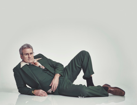 Studio shot of a mature man in a retro suit lying down and striking a pose