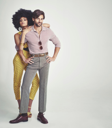 An attractive young couple standing together in retro 70s clothing