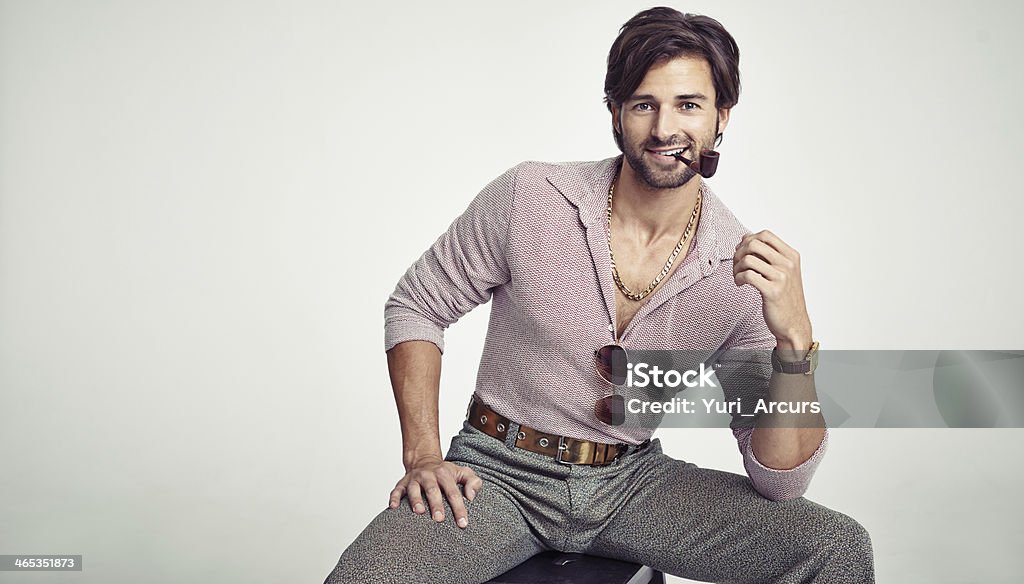 Rocking his retro look A young man with 70s style sitting in the studio and smoking a pipe 1970-1979 Stock Photo