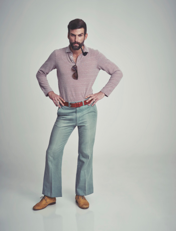 Studio shot of a handsome man striking a pose while wearing retro 70s style clothing