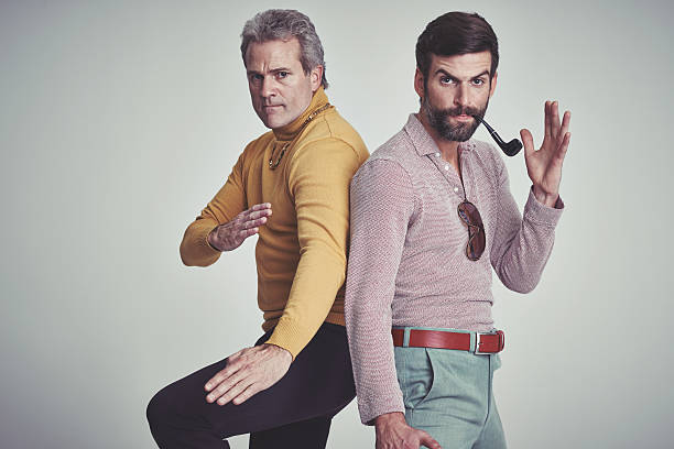 We can totally take you! Studio shot of two men standing together while wearing retro 70s wear and striking a fighting pose macho photos stock pictures, royalty-free photos & images
