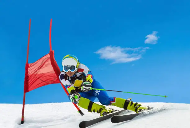 Front view of young female professional skier at giant slalom competition cup against the blue sky, real world cup competitor