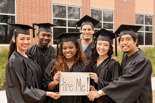 educaton: przyjaciele trzymając'hire me'szkoły znak po college. - high school student graduation education friendship zdjęcia i obrazy z banku zdjęć