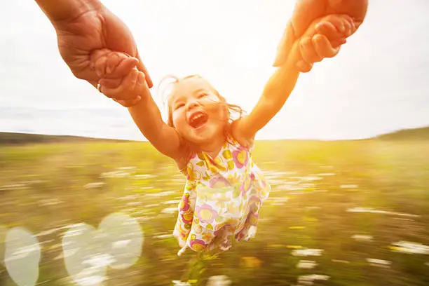 Happy girl spinning around her father in a field. Motion blur.