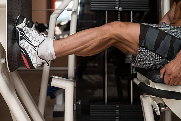 Male bodybuilder performing a seated leg press at the gym stock photo