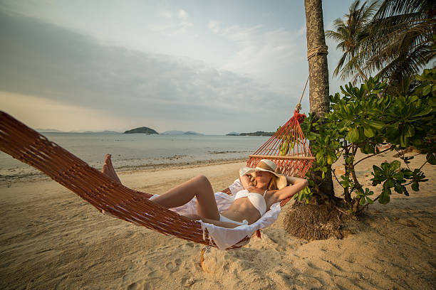 istock Young woman on beach lying down on hammock 465355796