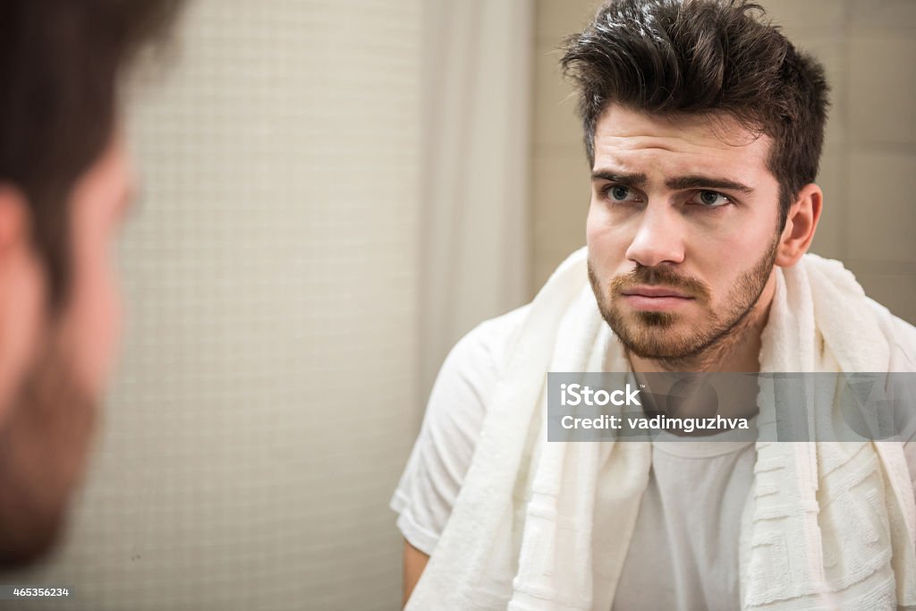 Vegetables Tired young man is looking at the mirror.Young handsome man holds pepper, isolated on white background. Mirror - Object Stock Photo