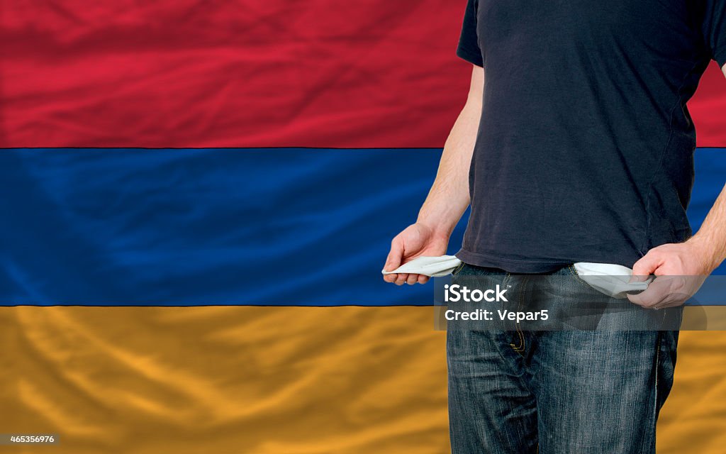 recession impact on young man and society in armenia poor man showing empty pockets in front of armenia flag 2015 Stock Photo