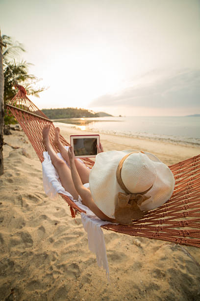 istock Young woman on beach with digital tablet 465357588