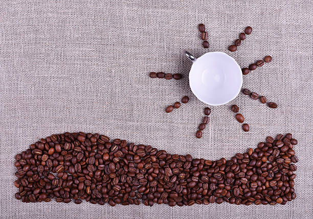 Composition cup of coffee with sun and sea coffee beans Composition cup of coffee with sun and sea made by coffee beans on linen texture table linen flax textile burlap stock pictures, royalty-free photos & images