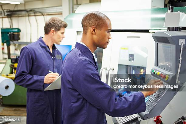 Engineer And Apprentice Using Automated Milling Machine Stock Photo - Download Image Now