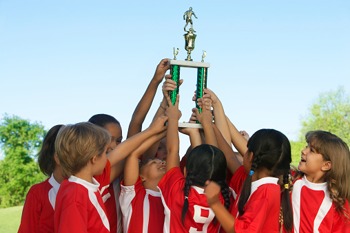 Group of children holding trophy above heads