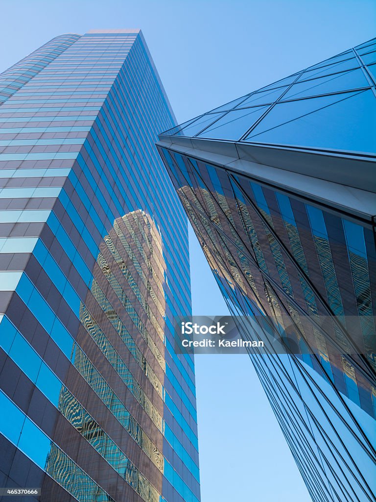 Reflective modern skyskrapers in Hong Kong Skyscrapers from a low angle perspective. The skyscrapers have glass front and reflected in the other. The background is a clear blue sky. 2015 Stock Photo