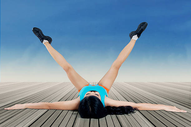 Young woman in sportswear lying on the floor and doing stretching exercise
