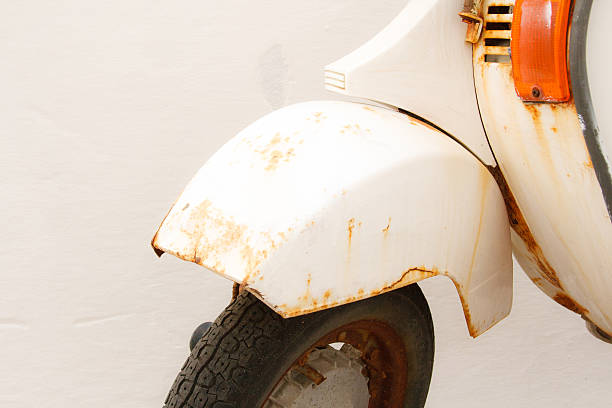 A detail of a vintage rusty white scooter against an old white wall in Italy. Shot on the island of Ponza in Italy.