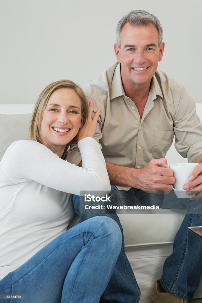 Portrait of couple with coffee cup in living room Portrait of a relaxed couple with coffee cup in living room at home Coffee - Drink Stock Photo