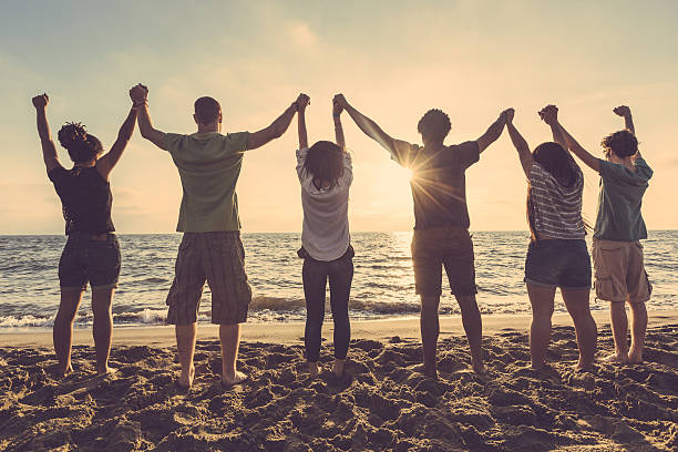 istock Multiracial group of people with raised arms looking at sunset 465383410