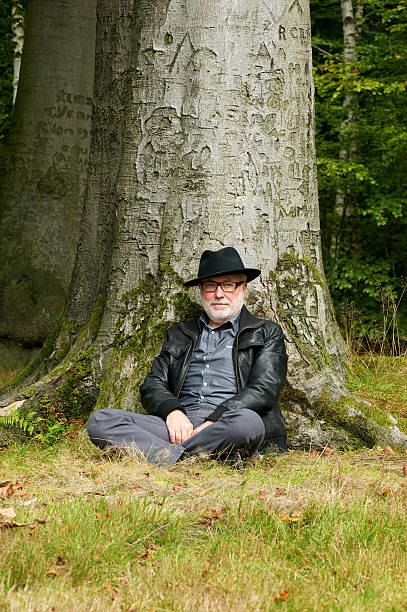 istock Old man sitting under tree in the park 465385943