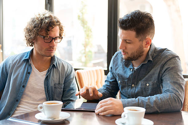 istock Men wearing denim sat with coffee looking at a tablet 465386288