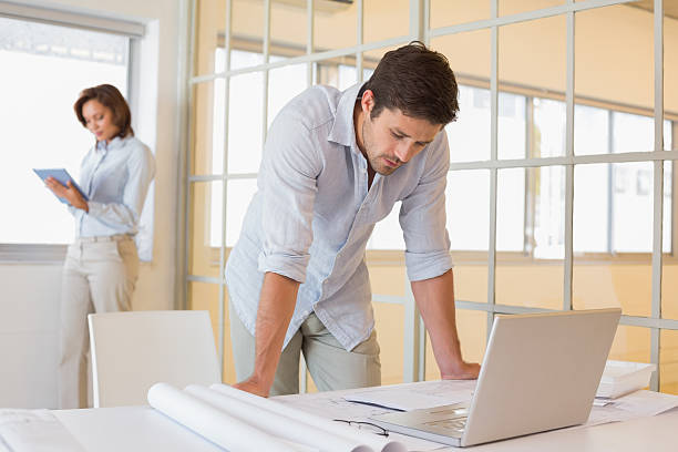istock Businessman using laptop with colleague in background 465387040