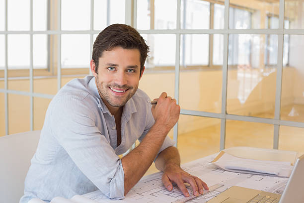 istock Smiling businessman working on blueprints in office 465387378