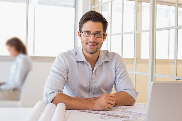 istock Smiling businessman working on blueprints at office 465387892
