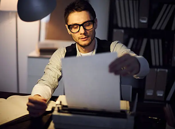 Handsome author typing on typewriter