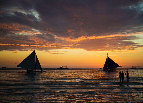 sunset and sailing boats on white beach in boracay philippines