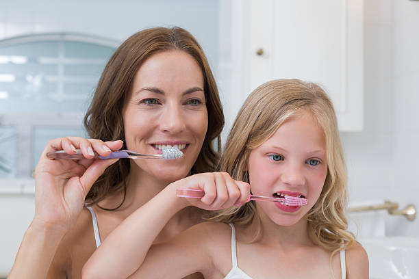 istock Mom and daughter brushing their teeth together 465389264