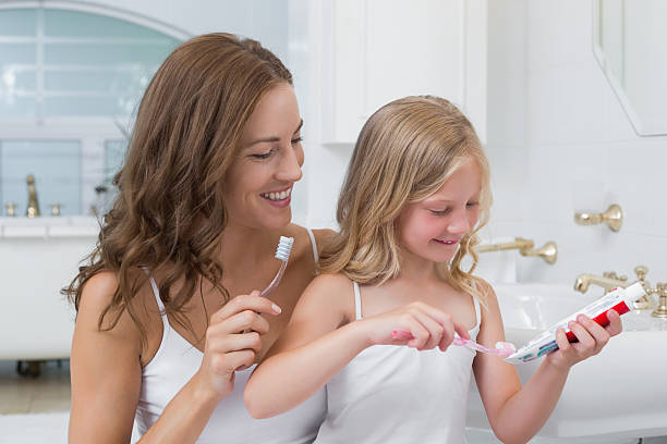 istock Mother and daughter brushing teeth in bathroom 465389718