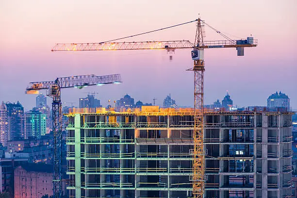 Photo of Construction of office building on purple sunset with two cranes