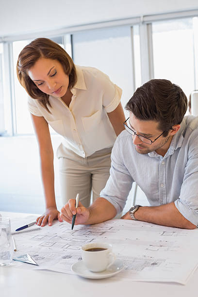 istock Concentrated colleagues working on blueprints at office 465390530