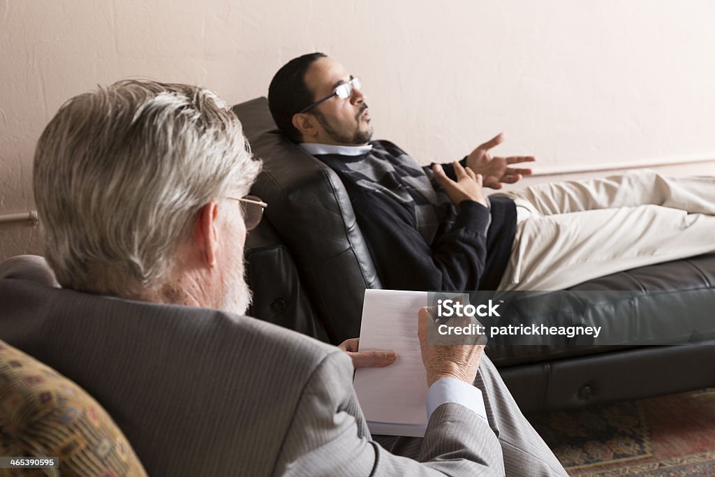 Therapy A man talks to a psychiatrist.  Focus is on the notes. Adult Stock Photo