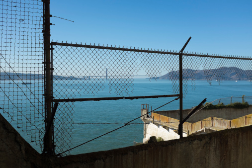Golden Gate Bridge seen through security fence on Alcatraz Island prison.