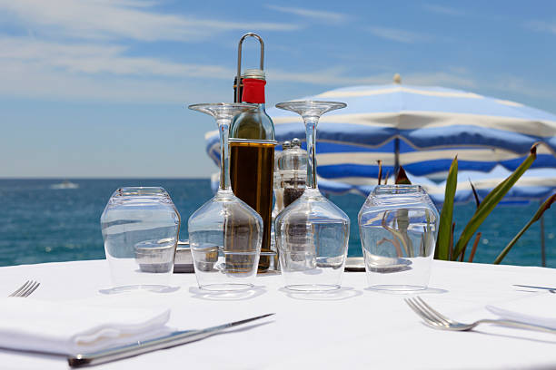 set table of a restaurant along the famous Promenade des Anglais in Nice with the Mediterranean Sea in the background; Nice, France